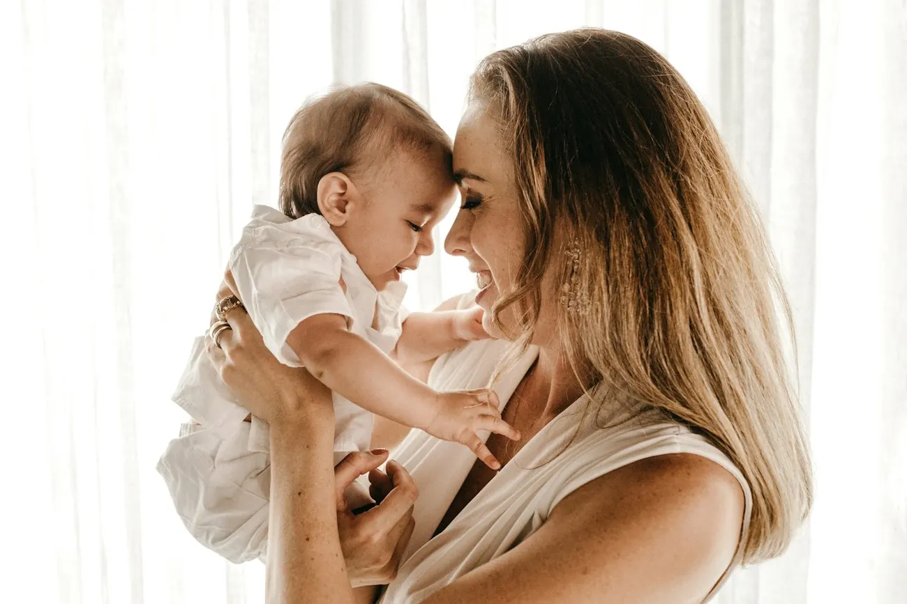 Una madre y su bebé, frente con frente, a contraluz