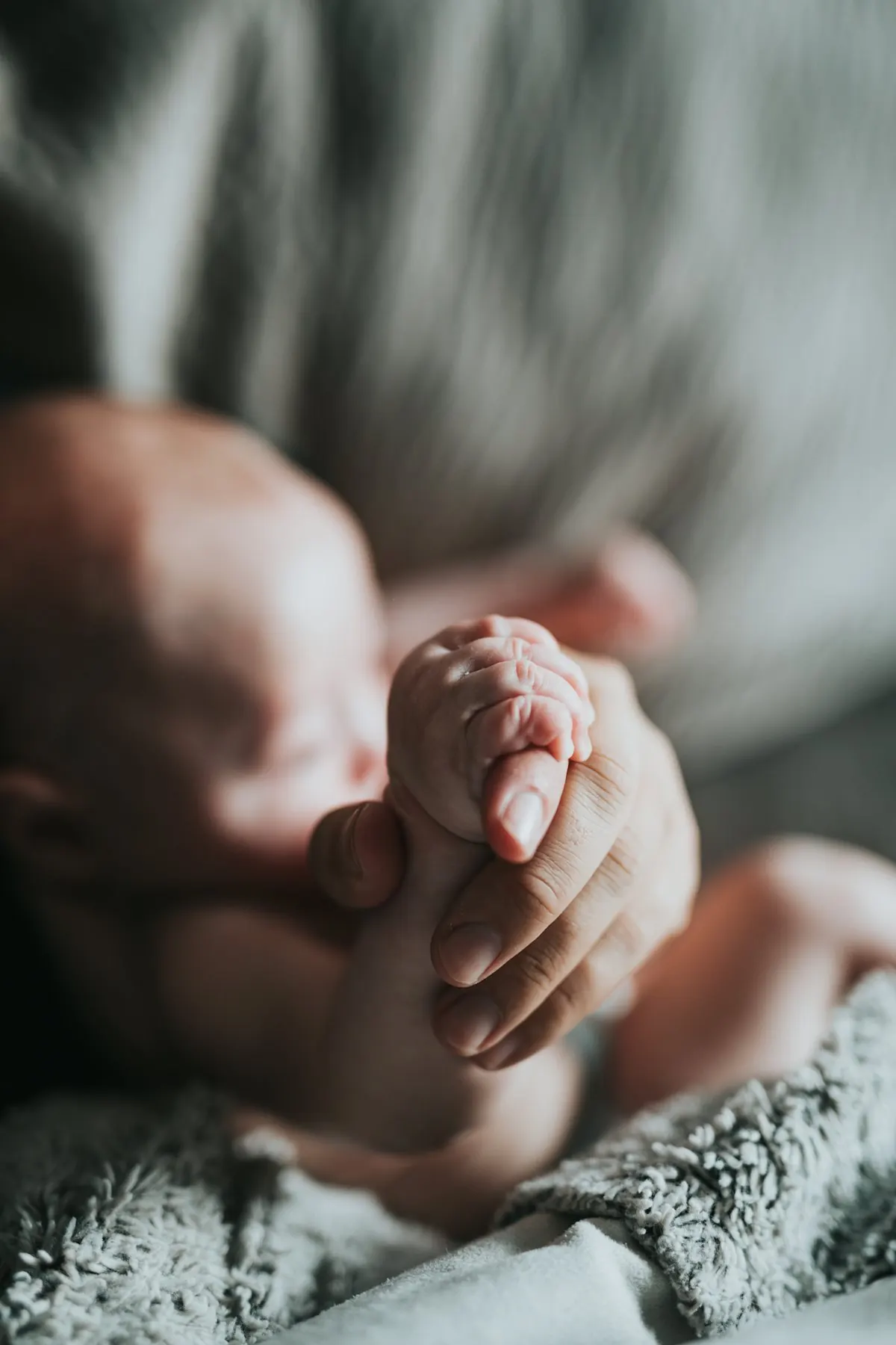 Las manos de un adulto sosteniendo la mano de un bebé